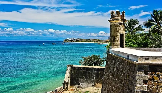 Vista aérea de Pampatar con su bahía y edificios costeros, una localidad con restaurantes frente al mar.