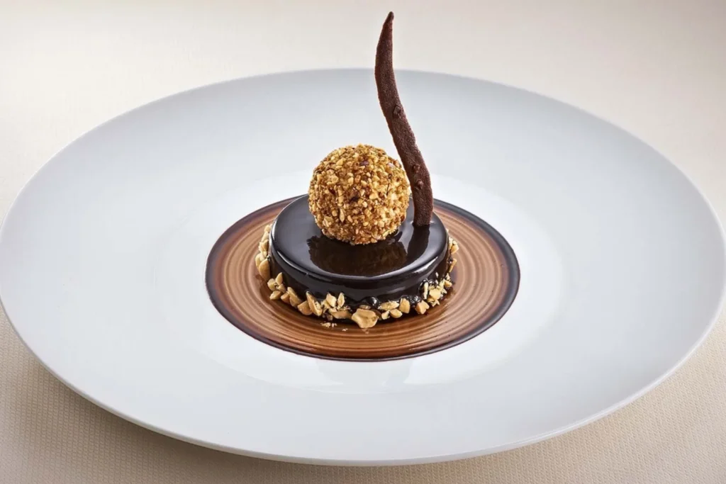 Postre gourmet de chocolate con esfera crocante y notas de caramelo, el final dulce de una cena inolvidable en Margarita.