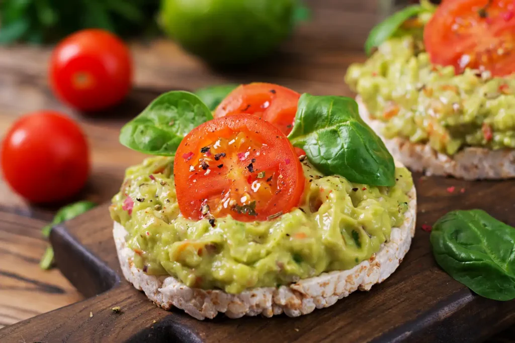 Tostadas vegetarianas con guacamole, tomate fresco y hojas de albahaca, servidas sobre tabla rústica en Margarita.