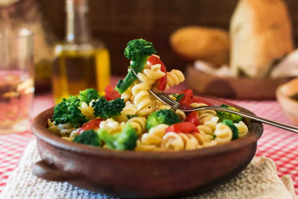 Ensalada de pasta fusilli con brócoli y tomate, servida en plato artesanal sobre mantel típico margariteño.