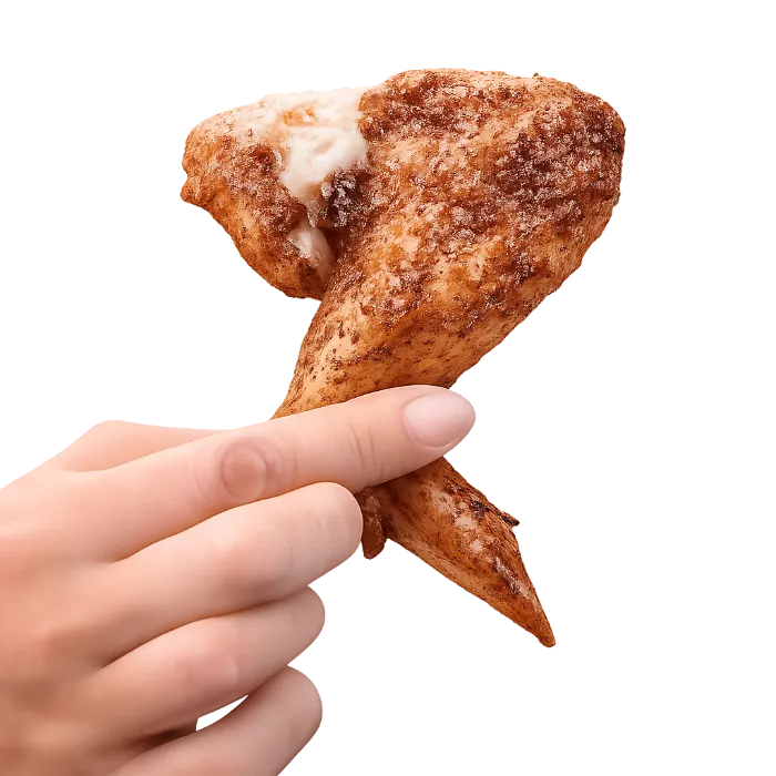 Pollo en Margarita, pieza de pollo asado sostenida con la mano sobre fondo blanco